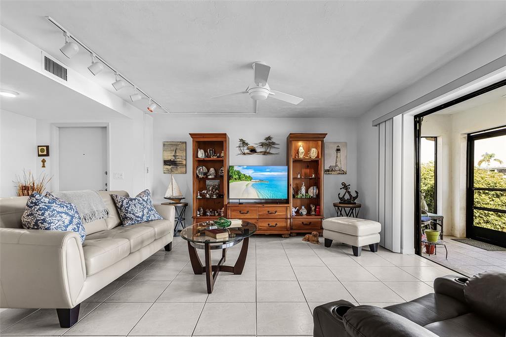 A living room features a beige sofa, a television on a wooden unit, and tile flooring — 3831 SE 11TH PLACE UNIT 101, CAPE CORAL, FL