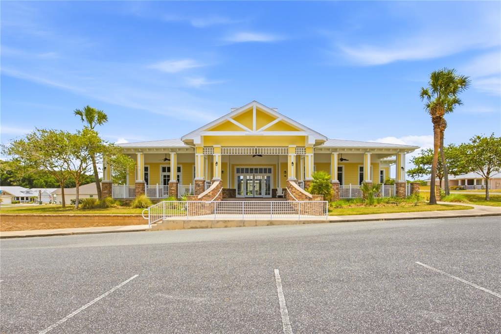 A modern kitchen features white cabinets, a central island with bar seating, and wood-look flooring — 6217 SANDERS GROVE CIRCLE, OKAHUMPKA, FL
