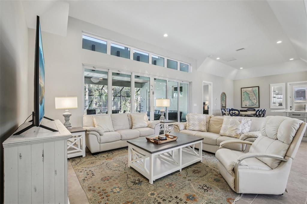 A bright living room features a white sofa, a recliner, and large glass sliding doors — 125 S BLVD OF PRESIDENTS, SARASOTA, FL