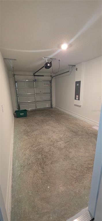 An empty one-car garage with a concrete floor, white walls, and an electrical panel — 7191 SW 92ND STREET, OCALA, FL