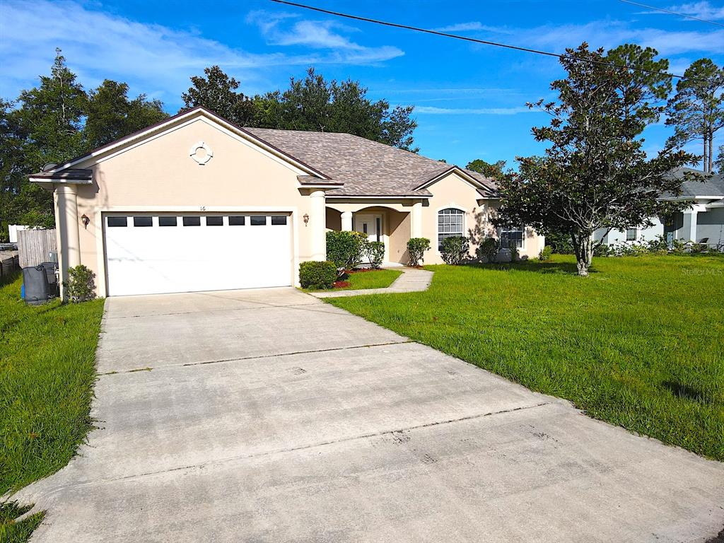 A single-story house with a beige stucco exterior, a two-car garage, and a concrete driveway — 16 ZORLOU COURT, PALM COAST, FL