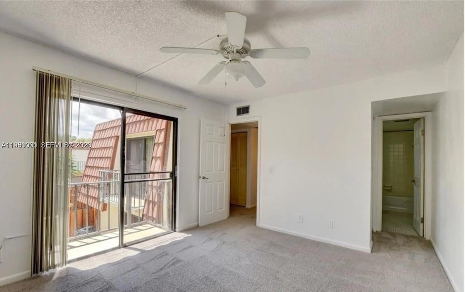 A bedroom with carpeted flooring, a ceiling fan, a sliding glass door, and two doorways — 3103 Spanish Wells dr # 2A, Delray Beach FL 33445, DELRAY BEACH, FL
