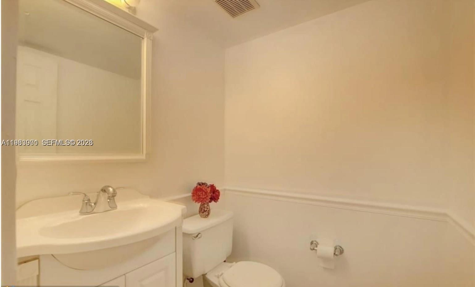 A small bathroom features a white vanity, a mirror, and a toilet against plain walls — 3103 Spanish Wells dr # 2A, Delray Beach FL 33445, DELRAY BEACH, FL