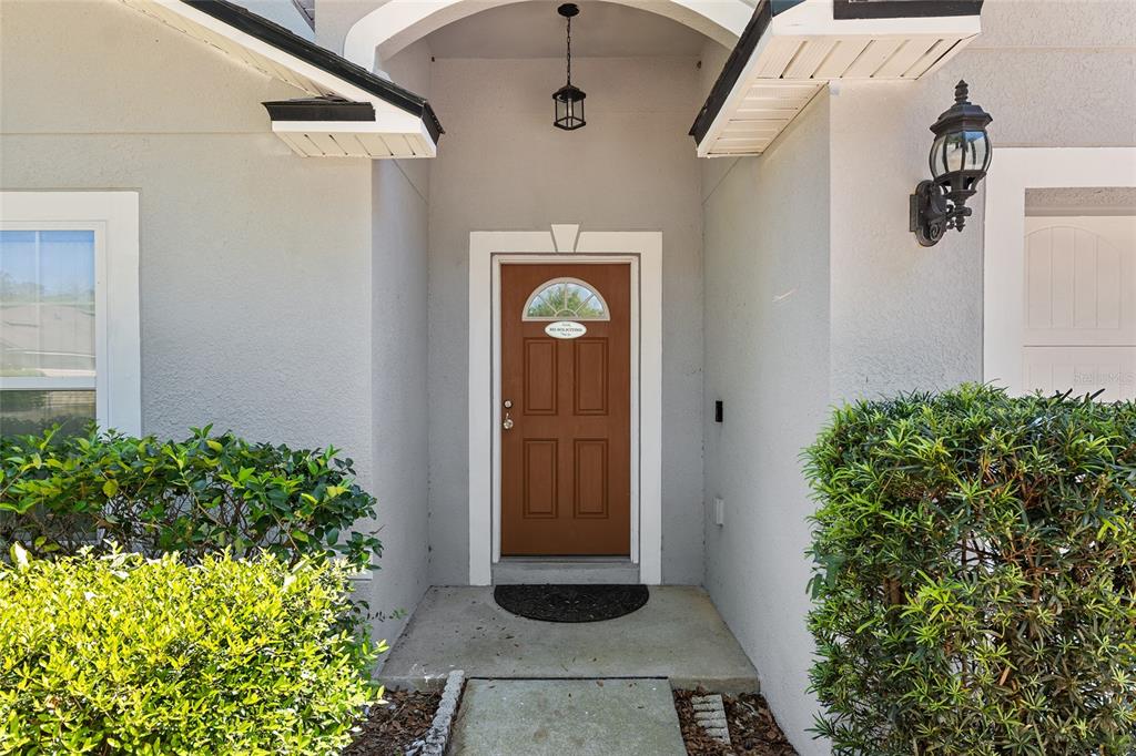 A brown front door is centered under a covered entryway with a hanging light fixture — 4939 NW 81ST AVENUE, GAINESVILLE, FL