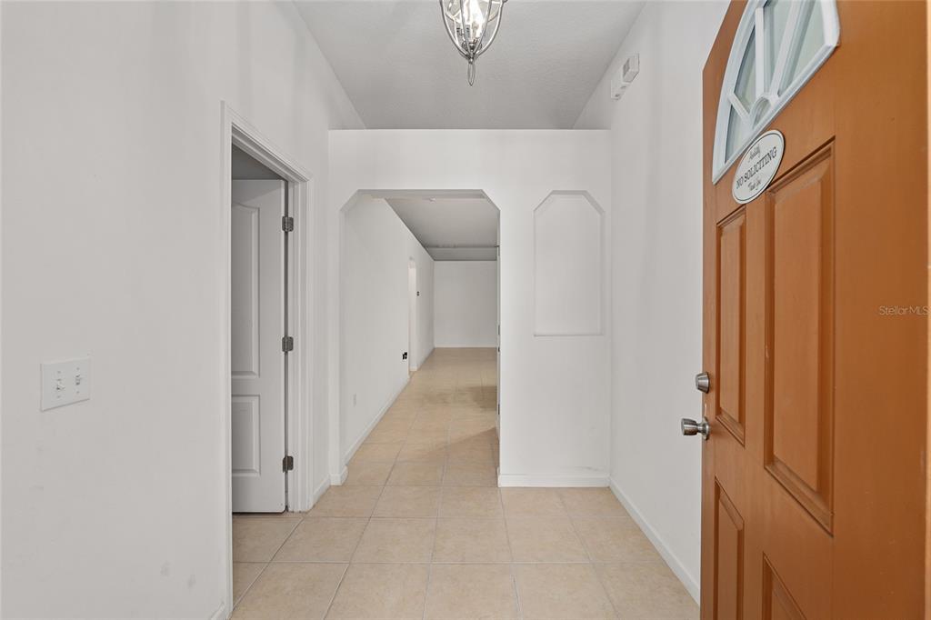 An entryway features a brown front door, tiled flooring, and a hallway leading inside — 4939 NW 81ST AVENUE, GAINESVILLE, FL