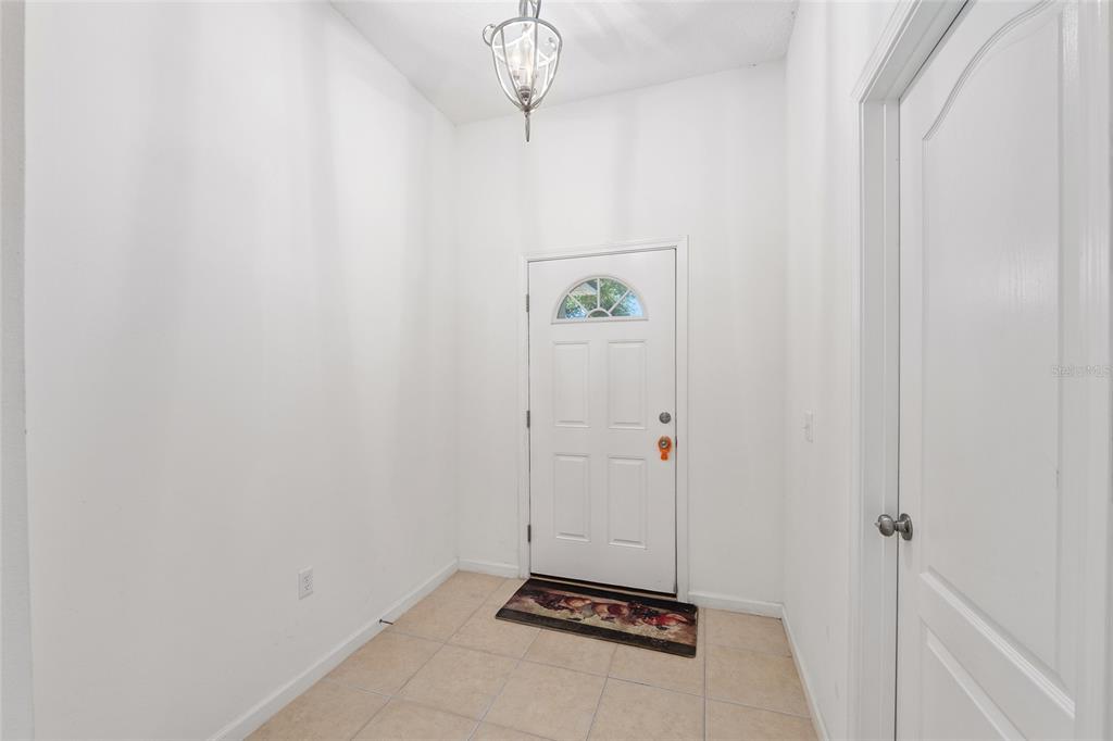 An entryway features white walls, a tiled floor, a white front door, and a hanging light — 4939 NW 81ST AVENUE, GAINESVILLE, FL