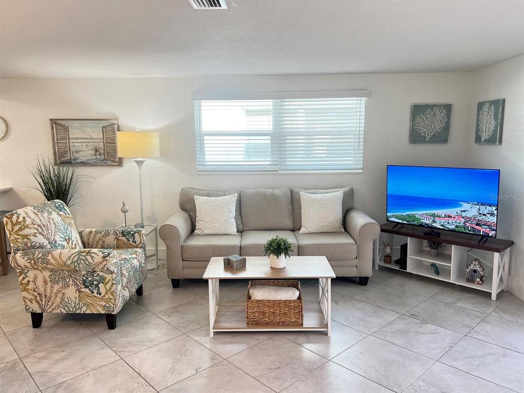 A living room features a beige sofa, patterned armchair, coffee table, and a television — 6154 MIDNIGHT PASS ROAD UNIT A04, SARASOTA, FL