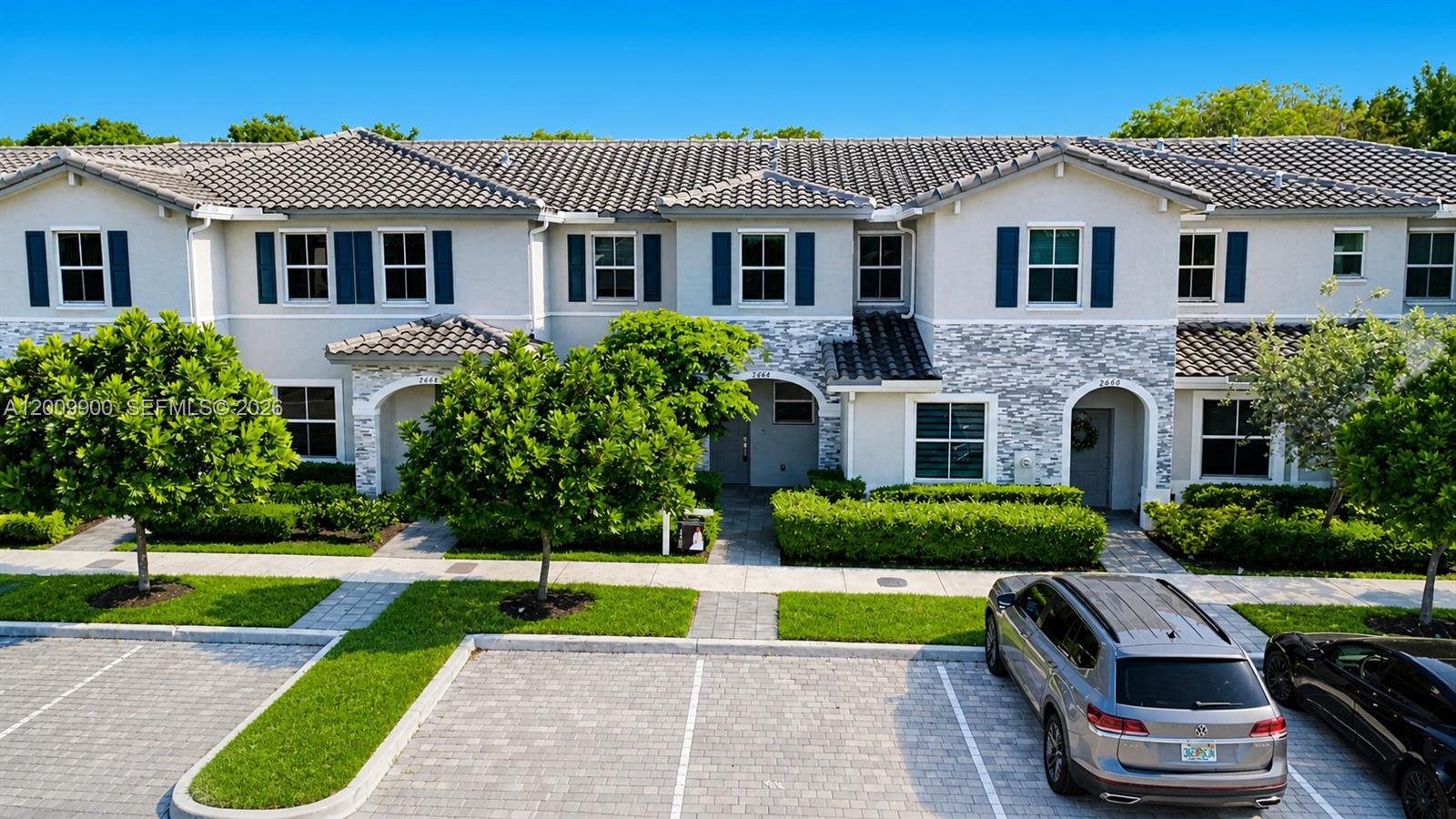 A two-story townhouse complex features a stone facade, dark shutters, and a paved parking lot — 2664 SE 19th St, Homestead FL 33035, HOMESTEAD, FL
