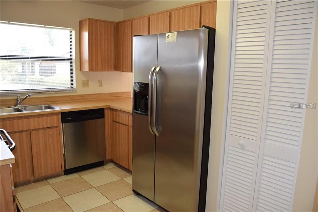 A kitchen features wood cabinets, stainless steel appliances, a double sink, and tiled flooring — 470 HUNTER CIRCLE, KISSIMMEE, FL