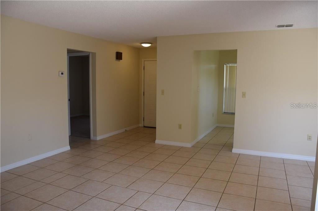 An empty room with beige walls and light-colored square floor tiles — 470 HUNTER CIRCLE, KISSIMMEE, FL