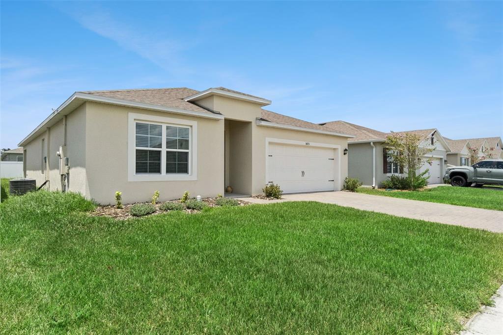 A single-story beige stucco house with a two-car garage and a front lawn — 5805 ARBORETUM STREET, ST CLOUD, FL