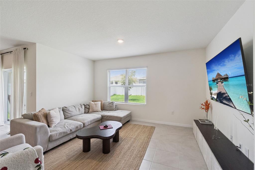 A living room features a light gray sectional sofa, a coffee table, and a wall-mounted television — 5805 ARBORETUM STREET, ST CLOUD, FL