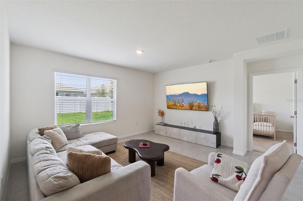 A living room features a sectional sofa, a coffee table, and a wall-mounted television — 5805 ARBORETUM STREET, ST CLOUD, FL