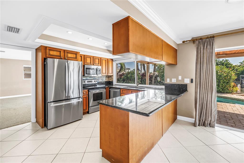 A kitchen sink with a stainless steel faucet overlooks a patio, pool, and canal view — 1820 TANGLEWOOD DRIVE NE, ST PETERSBURG, FL