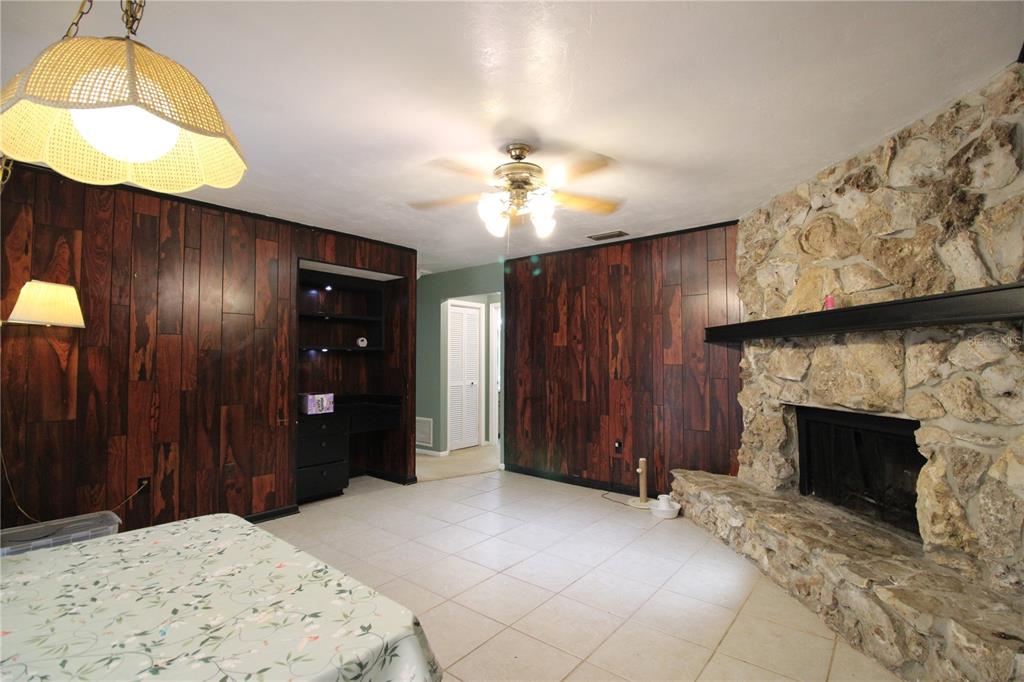 A living room features dark wood paneling, a stone fireplace, and light-colored tile flooring — 1624 SW 77TH TERRACE, GAINESVILLE, FL