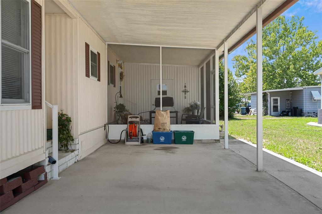 A concrete carport leads to a screened-in porch attached to a mobile home — 15299 BROOKRIDGE BOULEVARD, BROOKSVILLE, FL