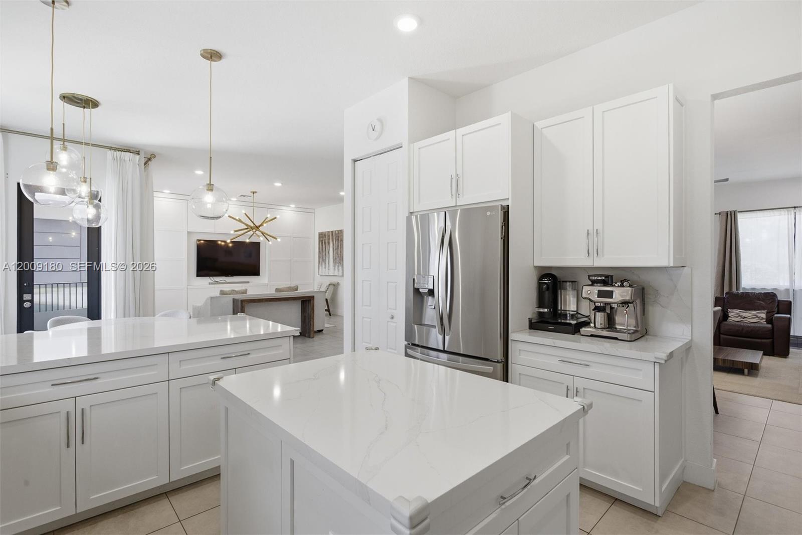 A modern white kitchen features a central island, stainless steel appliances, and quartz countertops — 10870 Windward St, Parkland FL 33076, PARKLAND, FL