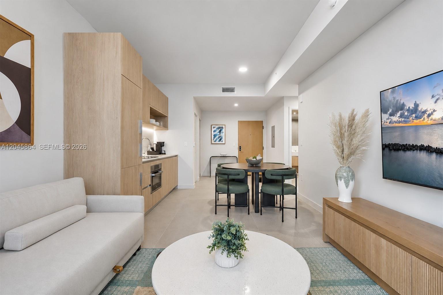 A modern open-concept living and dining area features light wood cabinetry and neutral furniture — 11 NE 6th St # 1712, Miami FL 33132, MIAMI, FL