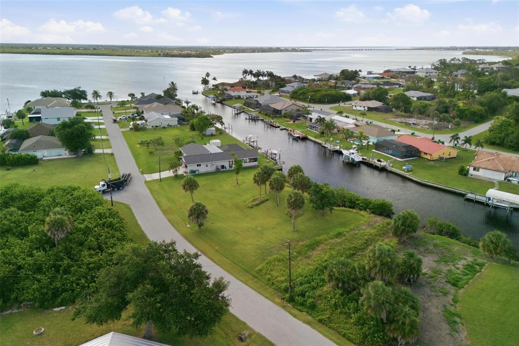 An aerial view shows a residential street, a canal with docked boats, and waterfront homes — 12397 & 12405 MITCHELL TERRACE, PORT CHARLOTTE, FL