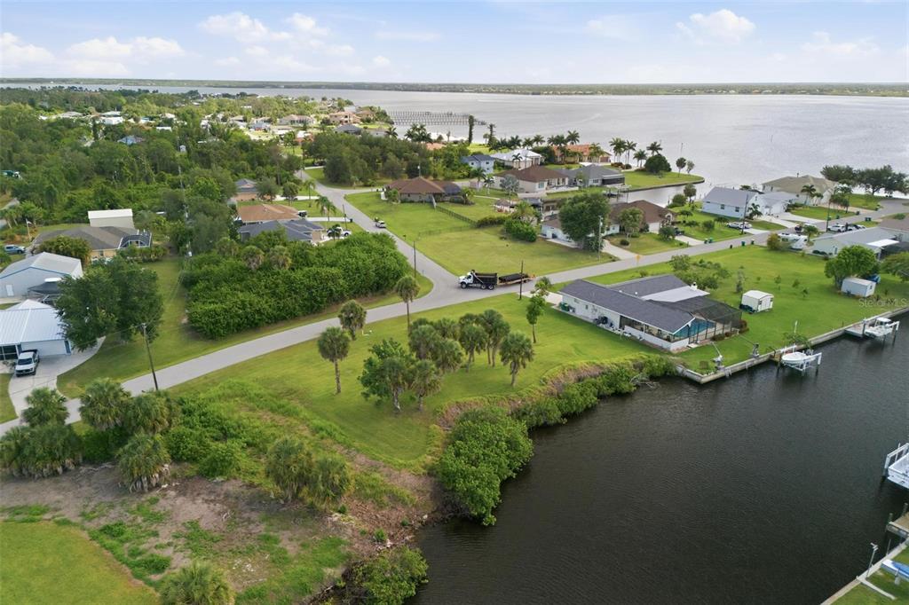 An aerial view shows waterfront homes, a road, and a truck near a canal — 12397 & 12405 MITCHELL TERRACE, PORT CHARLOTTE, FL