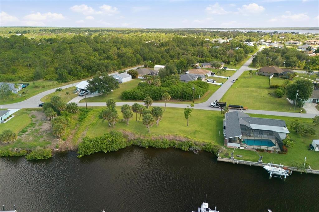 An aerial view shows a waterfront house with a pool near a road and trees — 12397 & 12405 MITCHELL TERRACE, PORT CHARLOTTE, FL