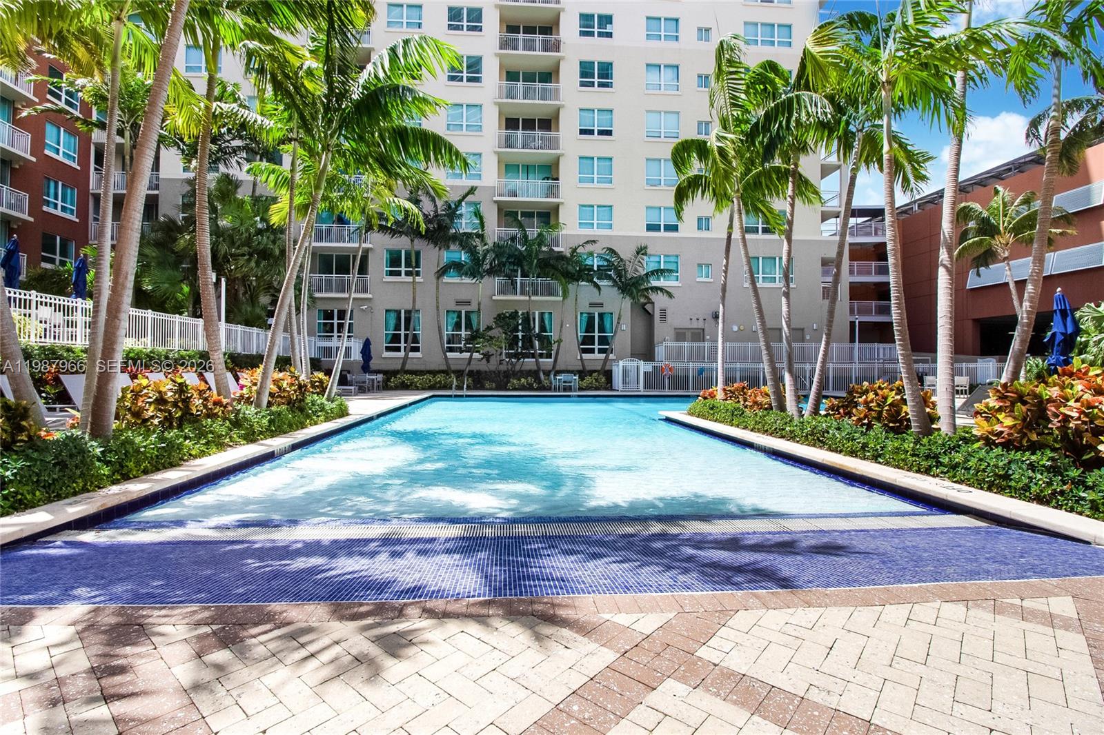 A rectangular swimming pool is surrounded by palm trees and a multi-story apartment building — 2000 N Bayshore Dr # 506, Miami FL 33137, MIAMI, FL