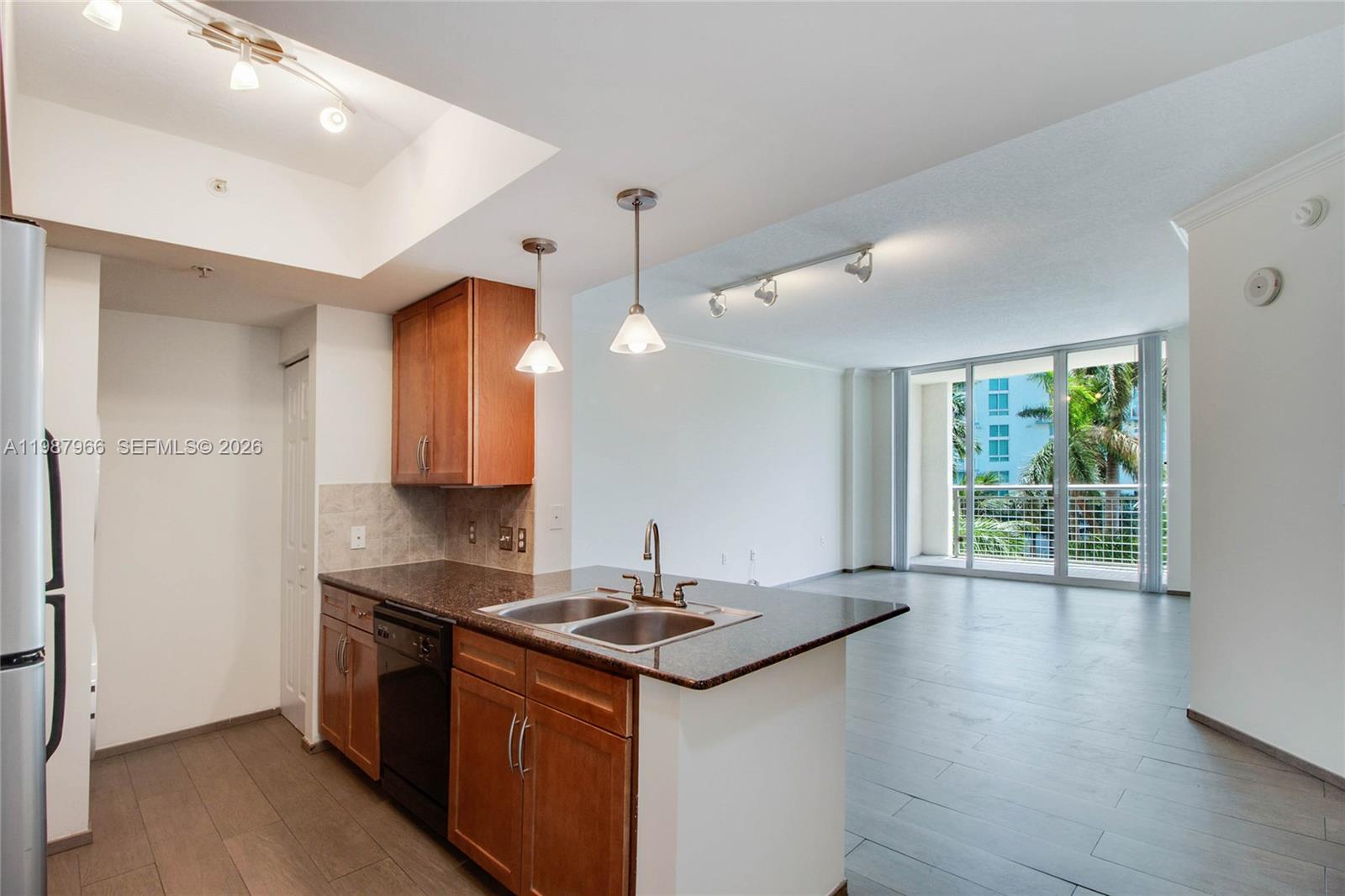 A kitchen with wood cabinets and granite countertops opens into a living area with balcony — 2000 N Bayshore Dr # 506, Miami FL 33137, MIAMI, FL