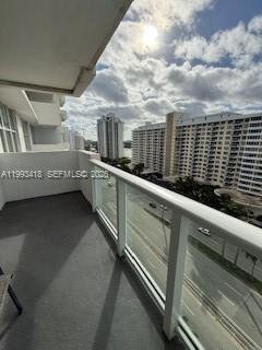 A balcony with a glass railing overlooks a city street and nearby high-rise buildings — 5601 Collins ave # 1219, Miami Beach FL 33140, MIAMI BEACH, FL