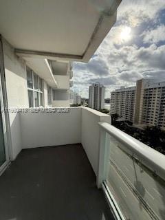 A balcony with a glass railing overlooks a city street and neighboring high-rise buildings — 5601 Collins ave # 1219, Miami Beach FL 33140, MIAMI BEACH, FL