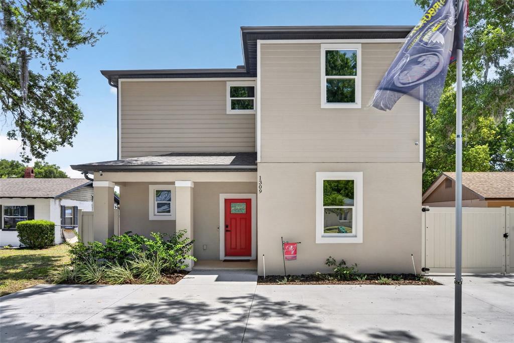 A two-story house with beige siding, a red front door, and a concrete driveway — 1309 S CENTER STREET, EUSTIS, FL