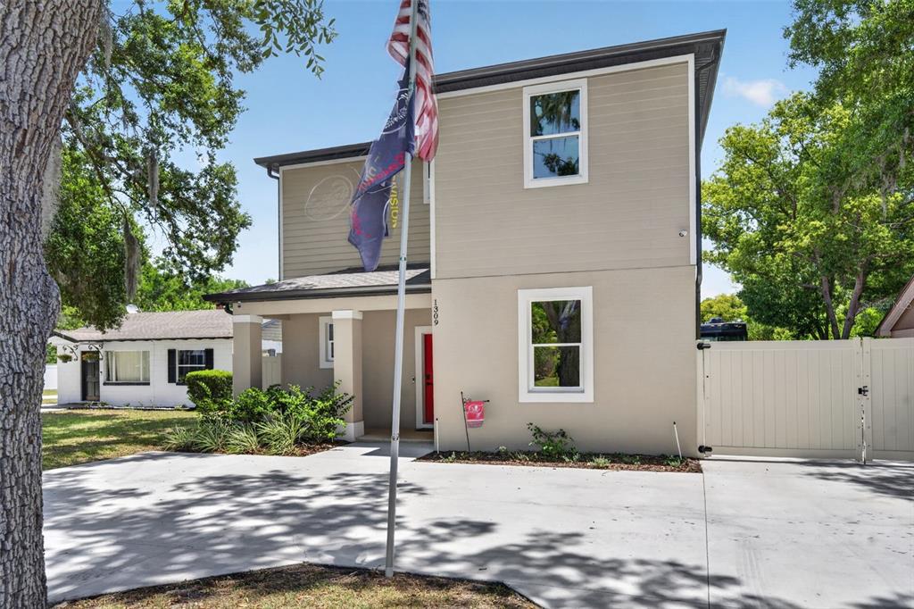 A two-story house with a concrete driveway, a flag pole, and a white privacy fence — 1309 S CENTER STREET, EUSTIS, FL