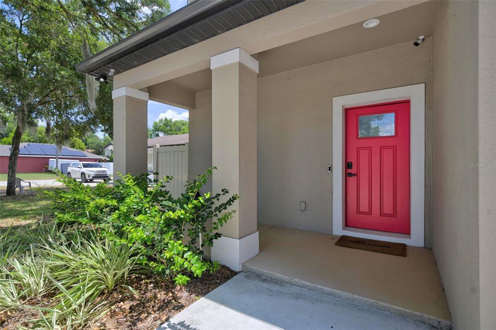 A covered front porch features a bright pink door and a concrete walkway — 1309 S CENTER STREET, EUSTIS, FL