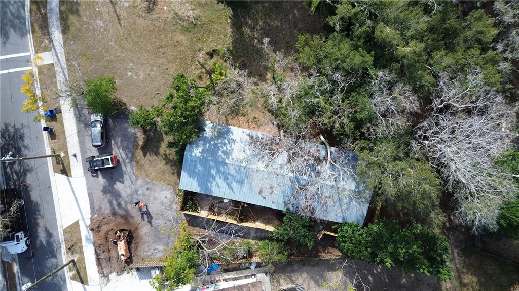 An aerial view shows a house with a metal roof surrounded by trees and construction equipment — 231 S ORANGE STREET, SEBRING, FL