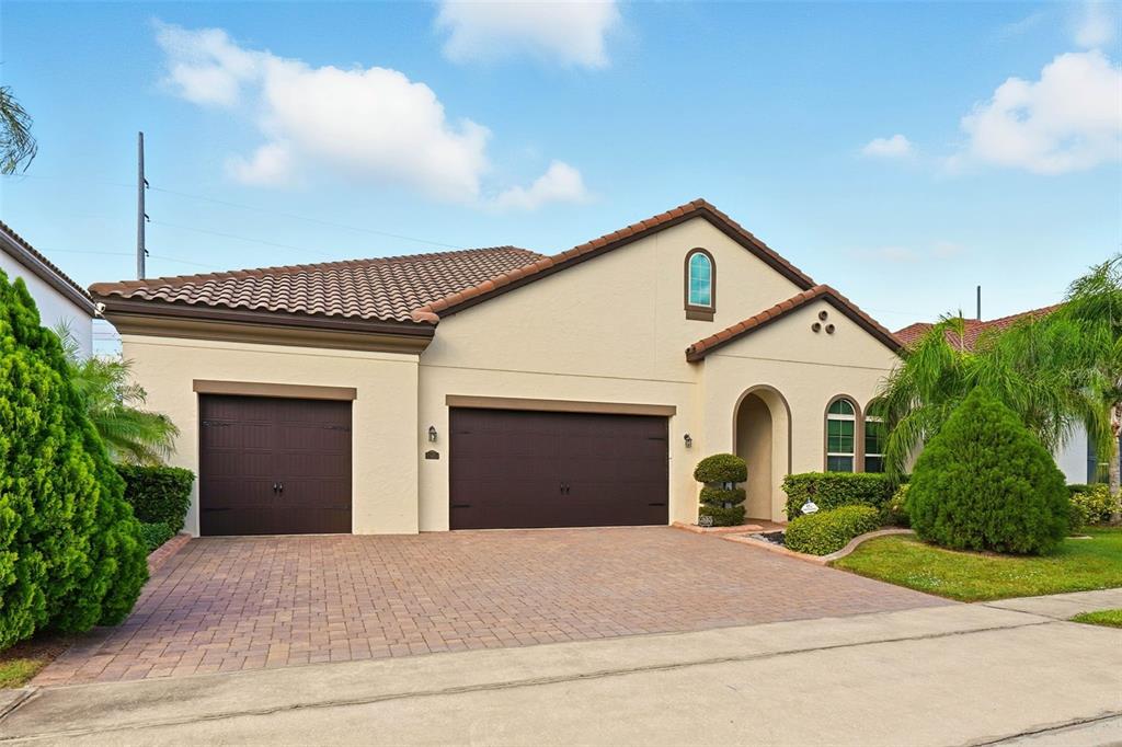 A single-story house with a tan stucco exterior, a tile roof, and two garage doors — 7945 CHILTON DRIVE, ORLANDO, FL
