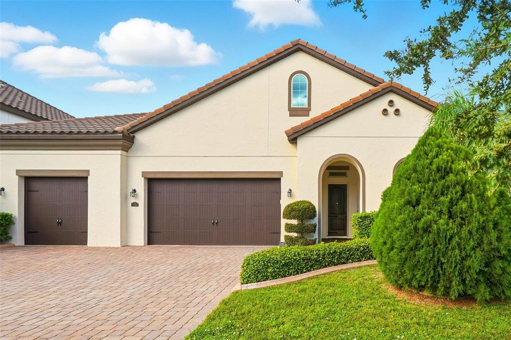 A single-story house with a two-car garage, a brick driveway, and a arched entryway — 7945 CHILTON DRIVE, ORLANDO, FL