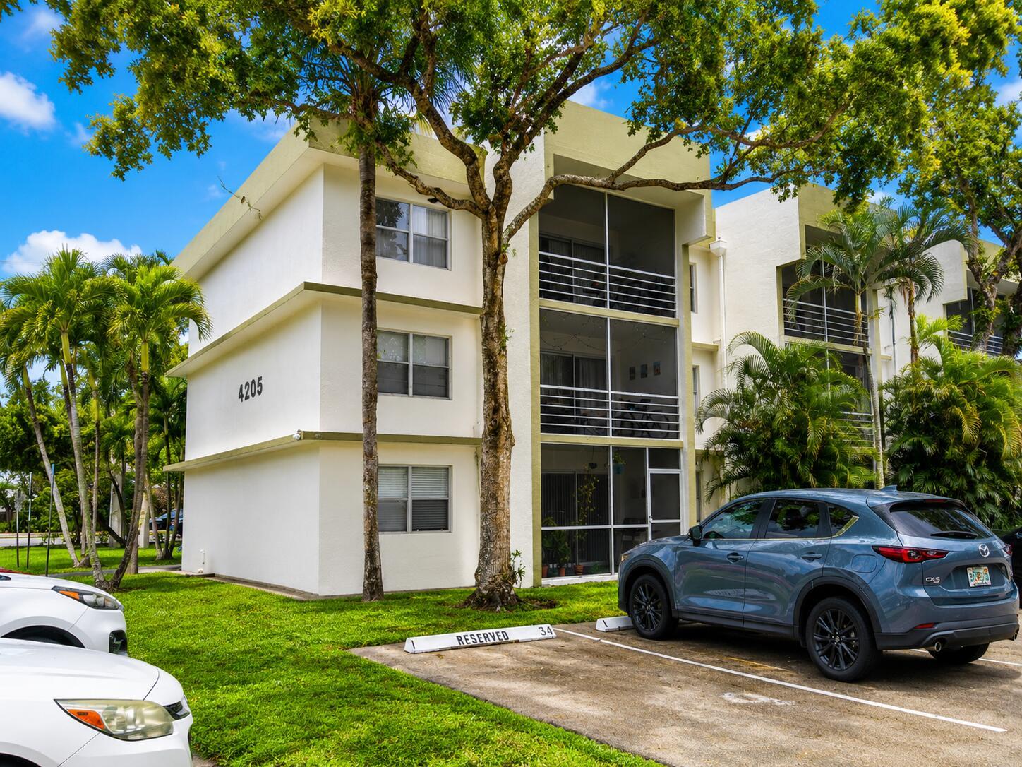 A three-story apartment building with a blue SUV parked in front on a sunny day — 4205 N University Drive # 106, Sunrise FL 33351, SUNRISE, FL