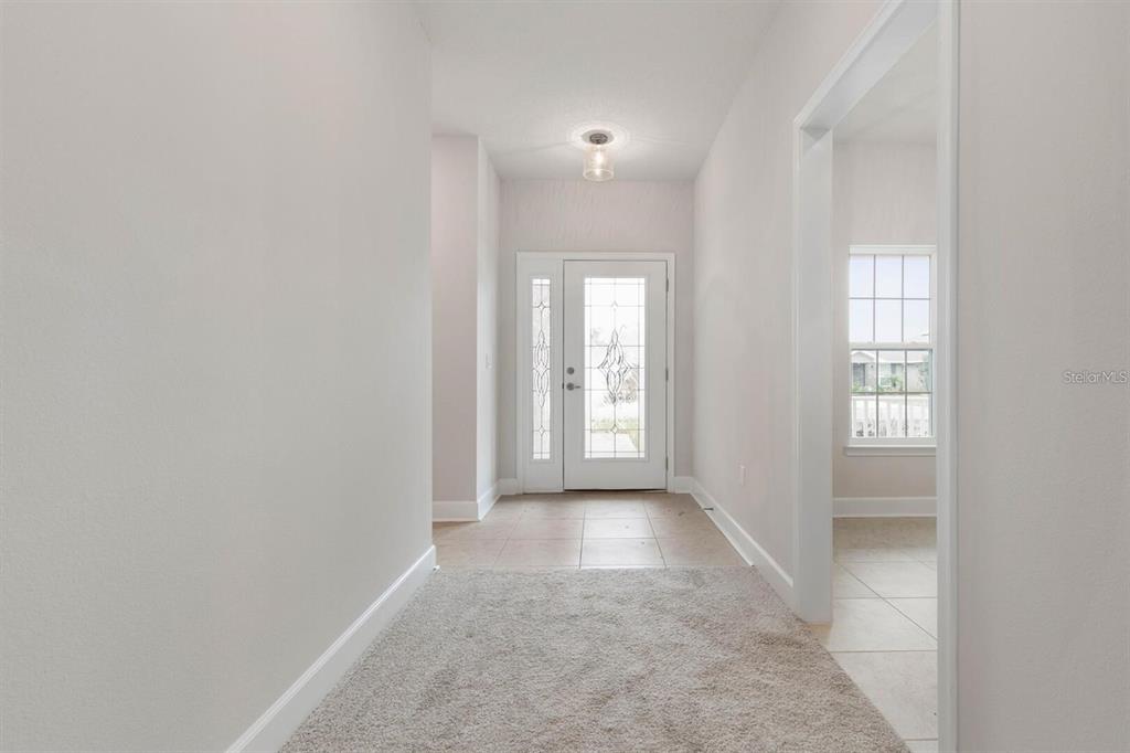 An entryway features a white front door with glass panels, tile flooring, and carpet — 59 RADCLIFFE  DRIVE, PALM COAST, FL