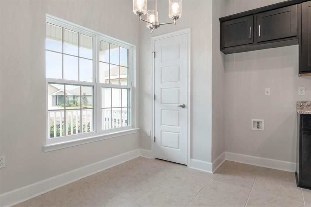 A bright room with tile flooring, a white door, a chandelier, and dark upper cabinets — 59 RADCLIFFE  DRIVE, PALM COAST, FL