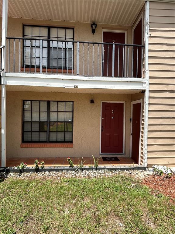 This two-story apartment building features a ground-level patio and an upper-level balcony with railings — 21027 VOYAGER BOULEVARD UNIT 7, LAND O LAKES, FL