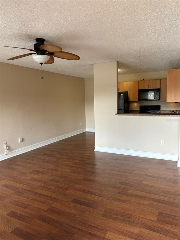 An open living area with wood-look flooring leads to a kitchen with light wood cabinets — 21027 VOYAGER BOULEVARD UNIT 7, LAND O LAKES, FL