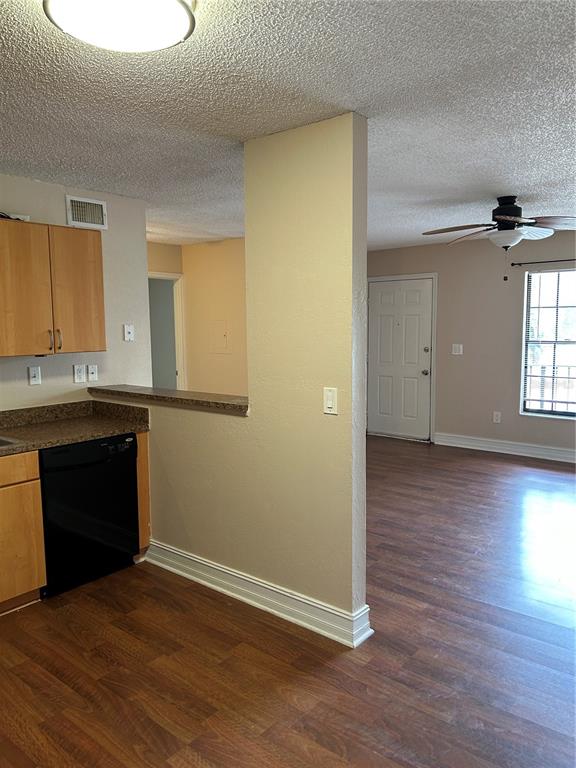 A kitchen with wood cabinets and a dishwasher opens into a living area with flooring — 21027 VOYAGER BOULEVARD UNIT 7, LAND O LAKES, FL