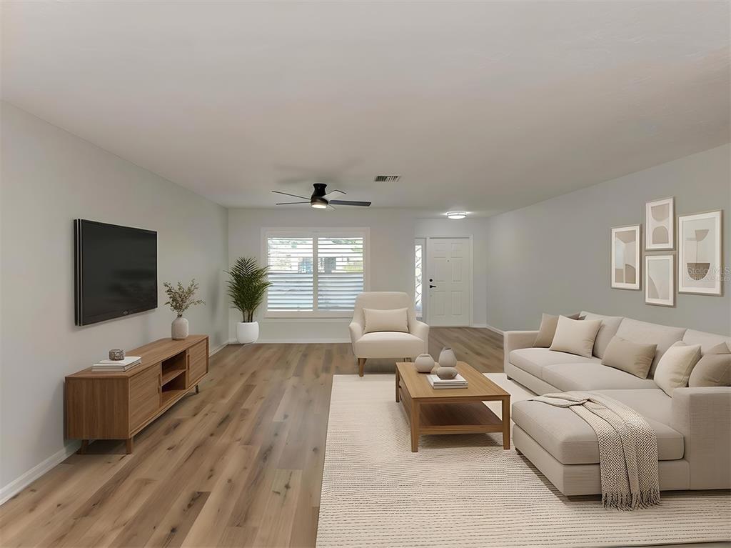 A living room features light wood flooring, a neutral sofa, a coffee table, and a television — 541 CARMEL ROAD, VENICE, FL