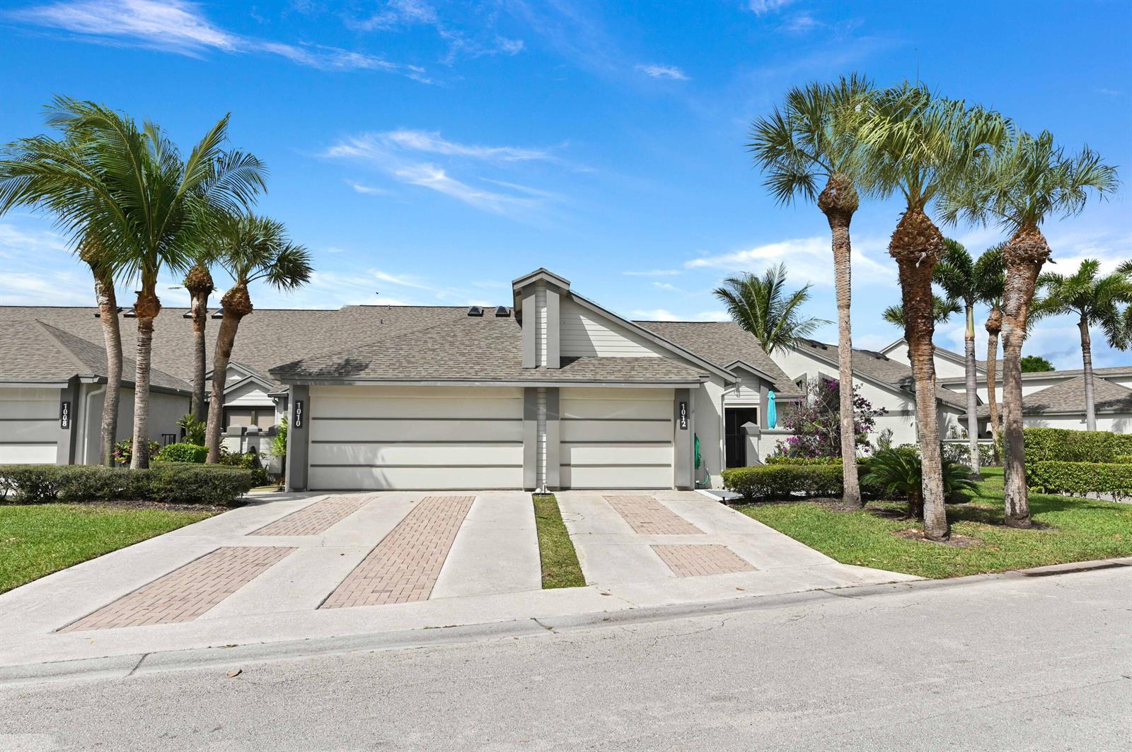 A duplex residential building features two garage doors, paved driveways, and several tall palm trees — 1012 Landings Boulevard, FL 33413, FL