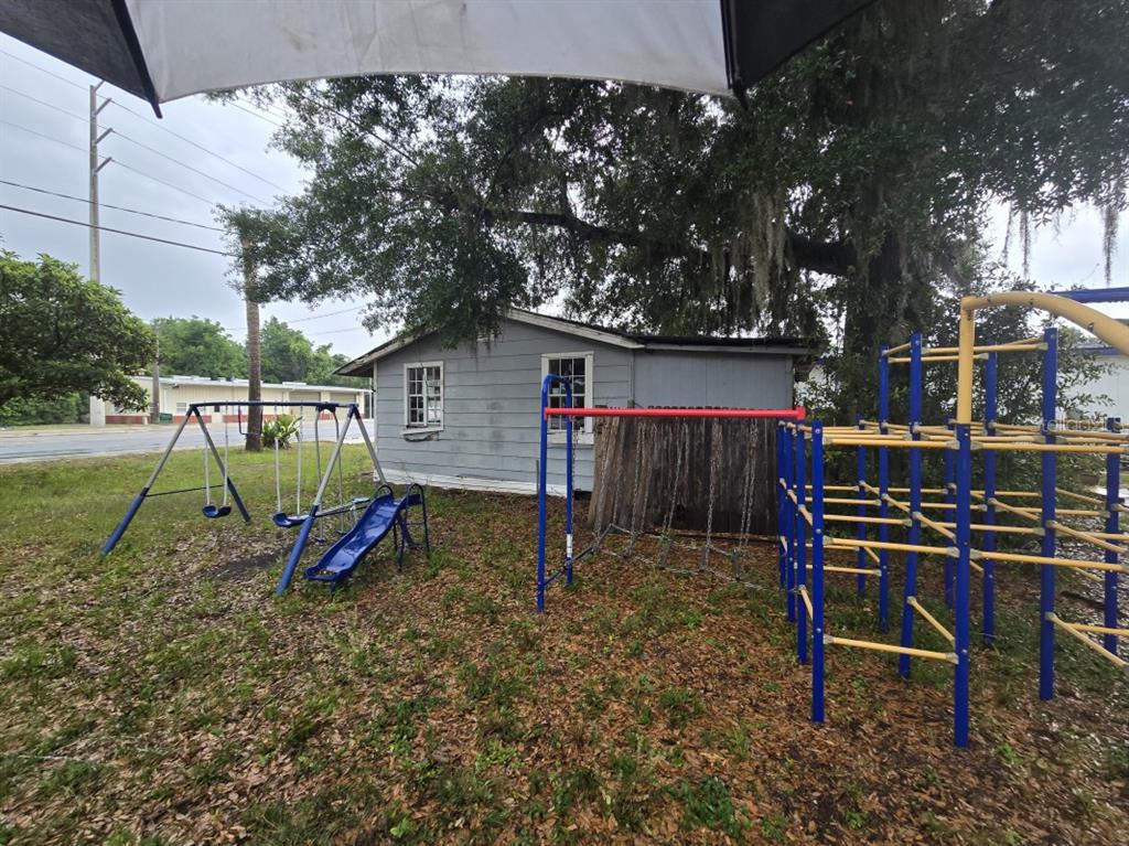 A backyard features a small gray house with a swing set and a jungle gym — 515 & 519 RONALD REAGAN PARKWAY, DAVENPORT, FL
