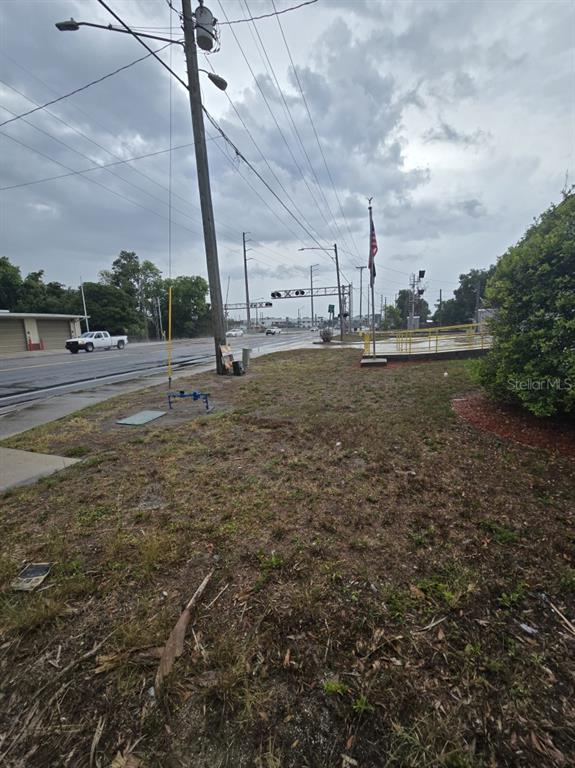 An outdoor view of a grassy lot with a utility pole, road, and railroad crossing — 515 & 519 RONALD REAGAN PARKWAY, DAVENPORT, FL