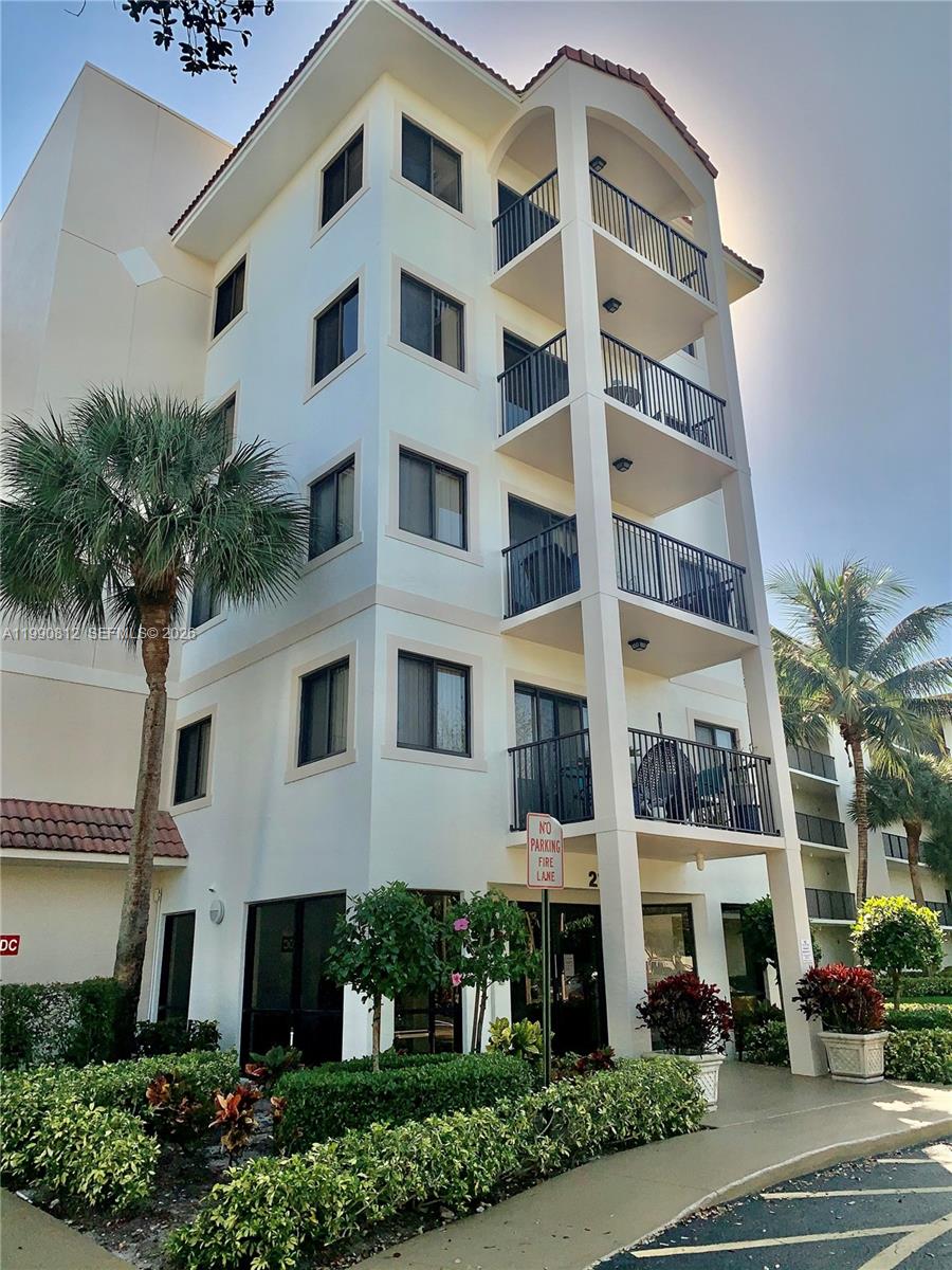 A multi-story white apartment building features stacked balconies and a palm tree in front — 2105 Lavers Cir # 501, Delray Beach FL 33444, DELRAY BEACH, FL