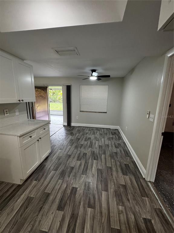 A kitchen area with white cabinets, light countertops, and wood-look flooring leads to a patio — 6346 SAINT ANDREWS CIRCLE S, FORT MYERS, FL