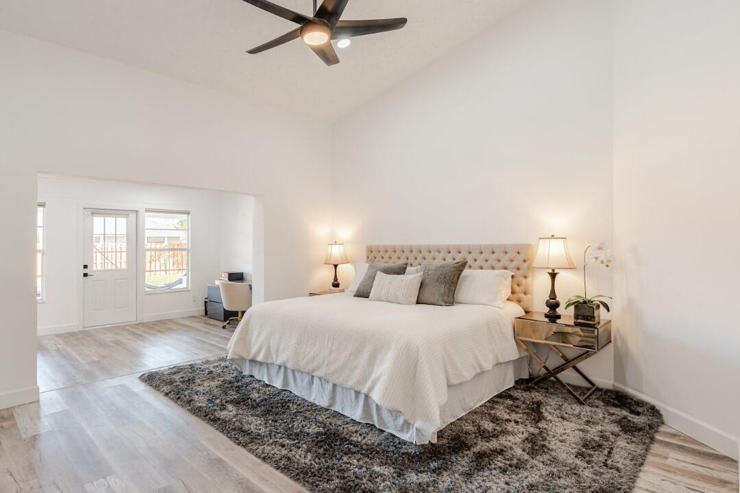 A spacious bedroom with a tufted headboard, gray area rug, and an adjoining office space — 1860 Primrose Lane, Wellington FL 33414, WELLINGTON, FL