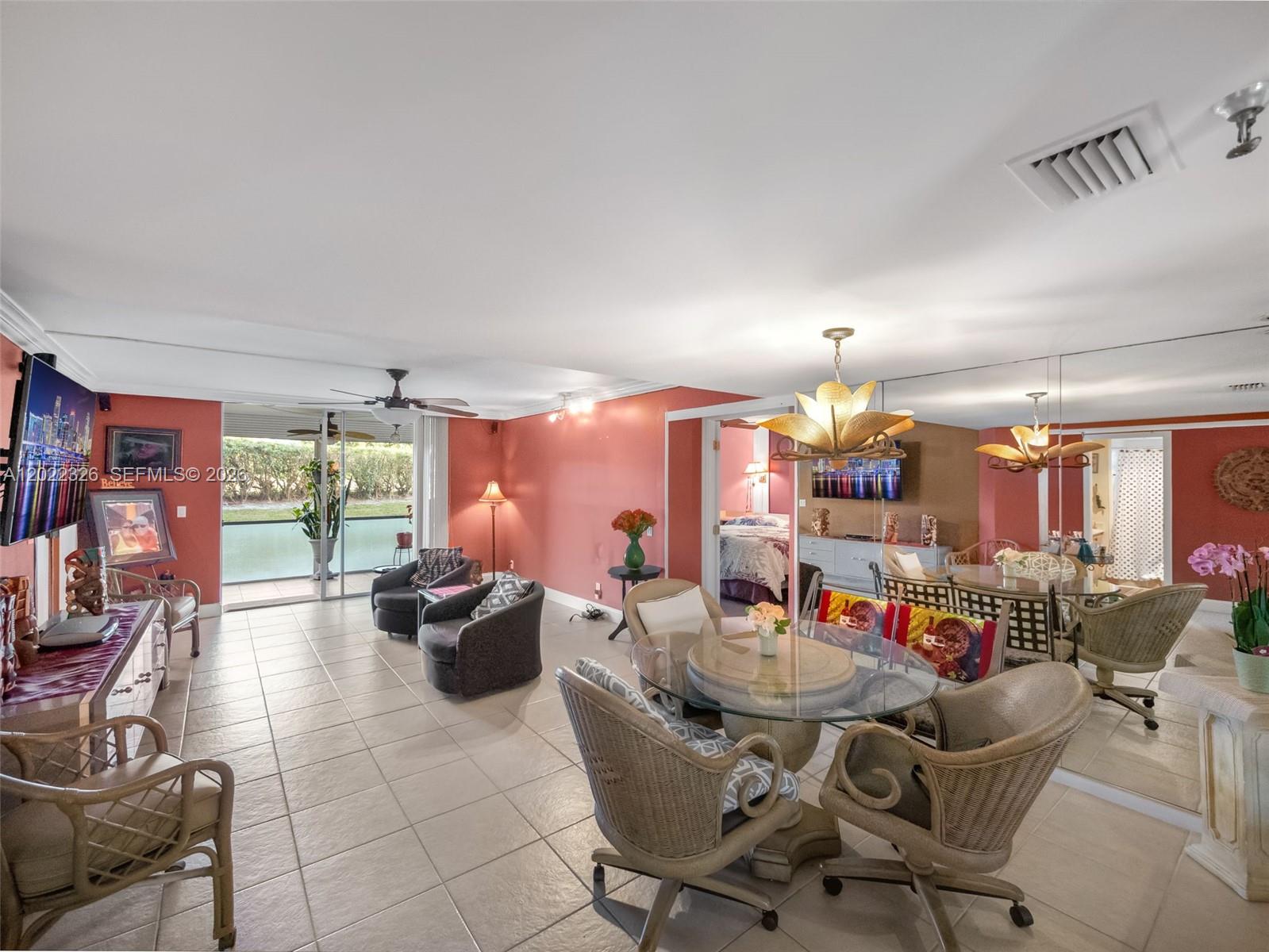 A living and dining area with coral walls, tile floors, and a glass-topped table — 6400 NW 2nd Ave # 117, Boca Raton FL 33487, BOCA RATON, FL