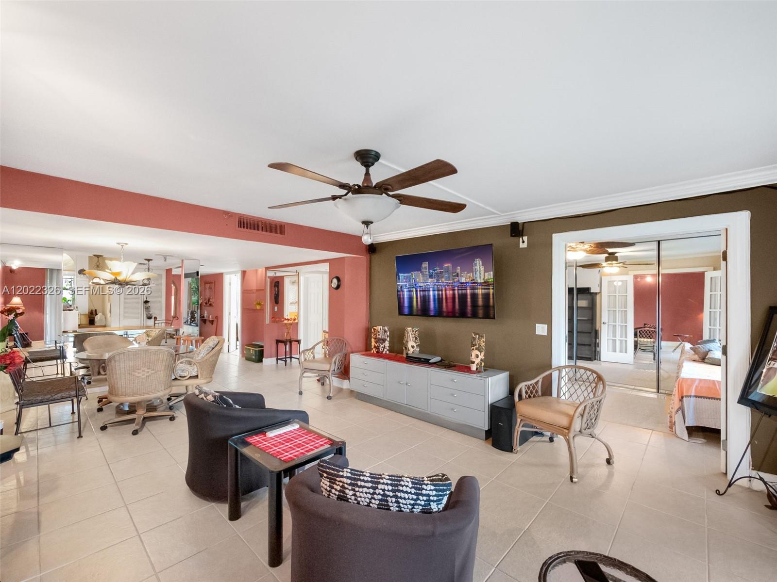 A living room features tile flooring, a ceiling fan, a wall-mounted television, and adjacent dining area — 6400 NW 2nd Ave # 117, Boca Raton FL 33487, BOCA RATON, FL